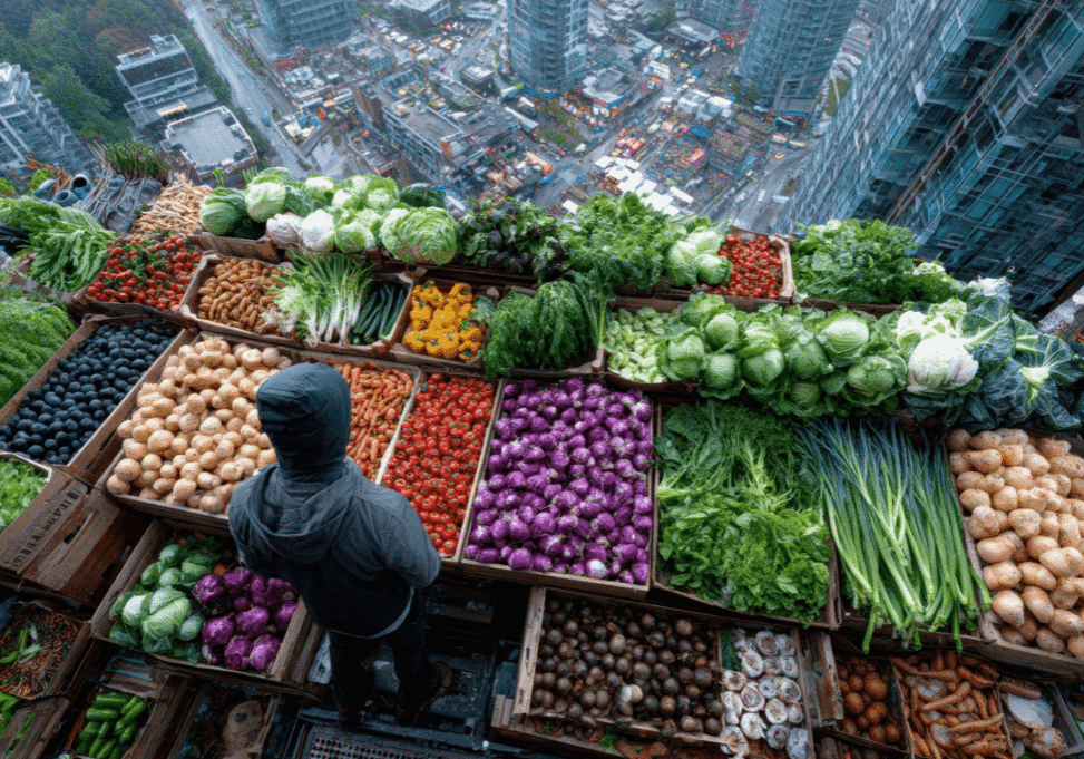 person standing in a fresh produce stall with view of city beyond